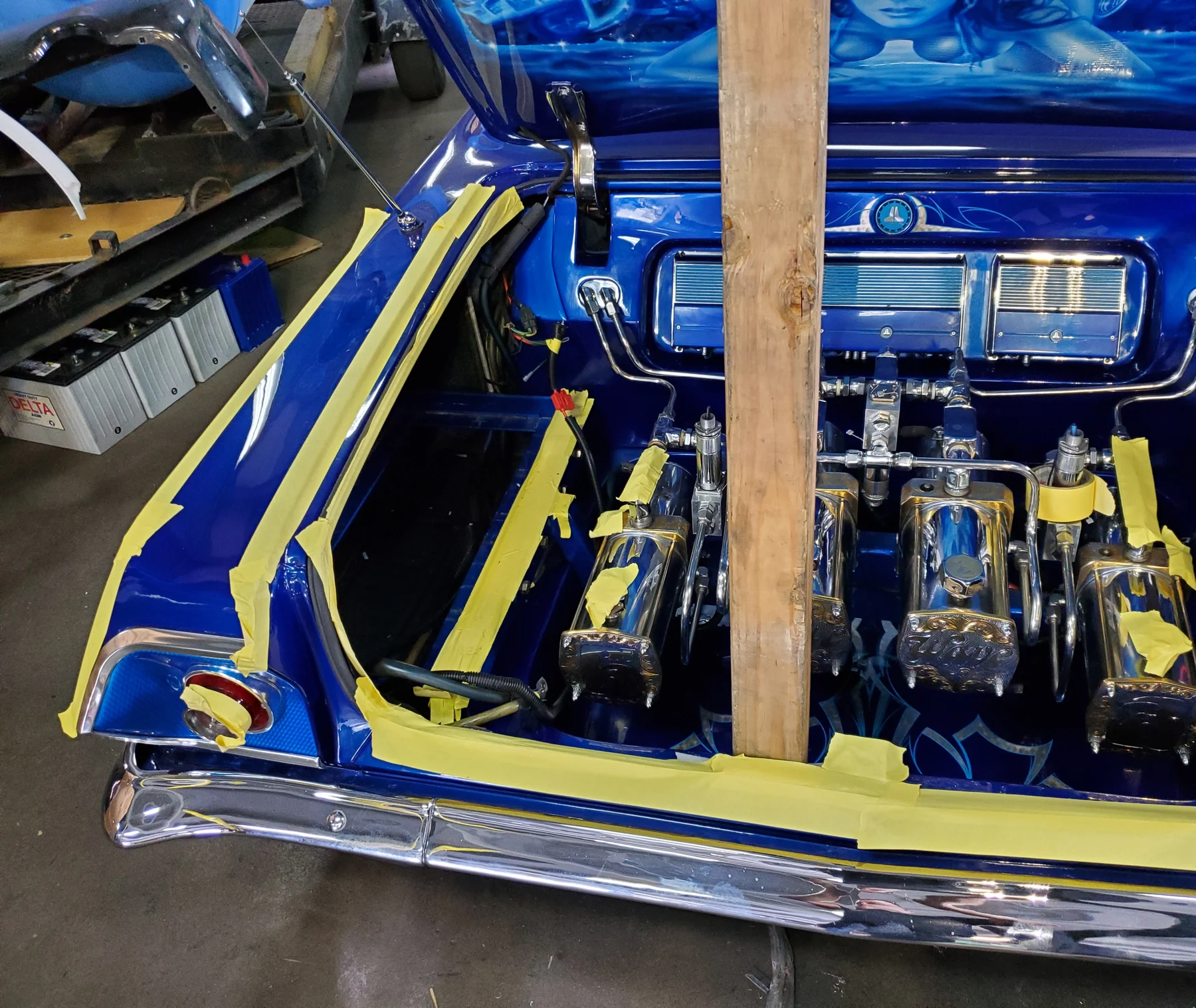 Blue custom trunk installation with polished hydraulic components and masked trim