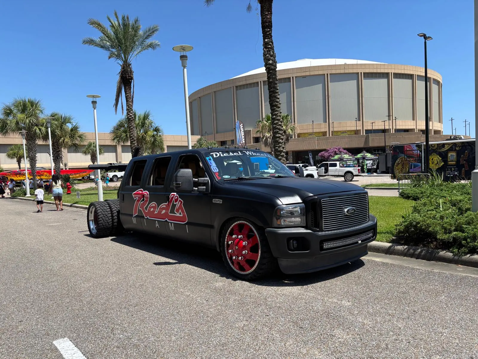 Black Red's Miami dually pickup on red wheels at an outdoor automotive show