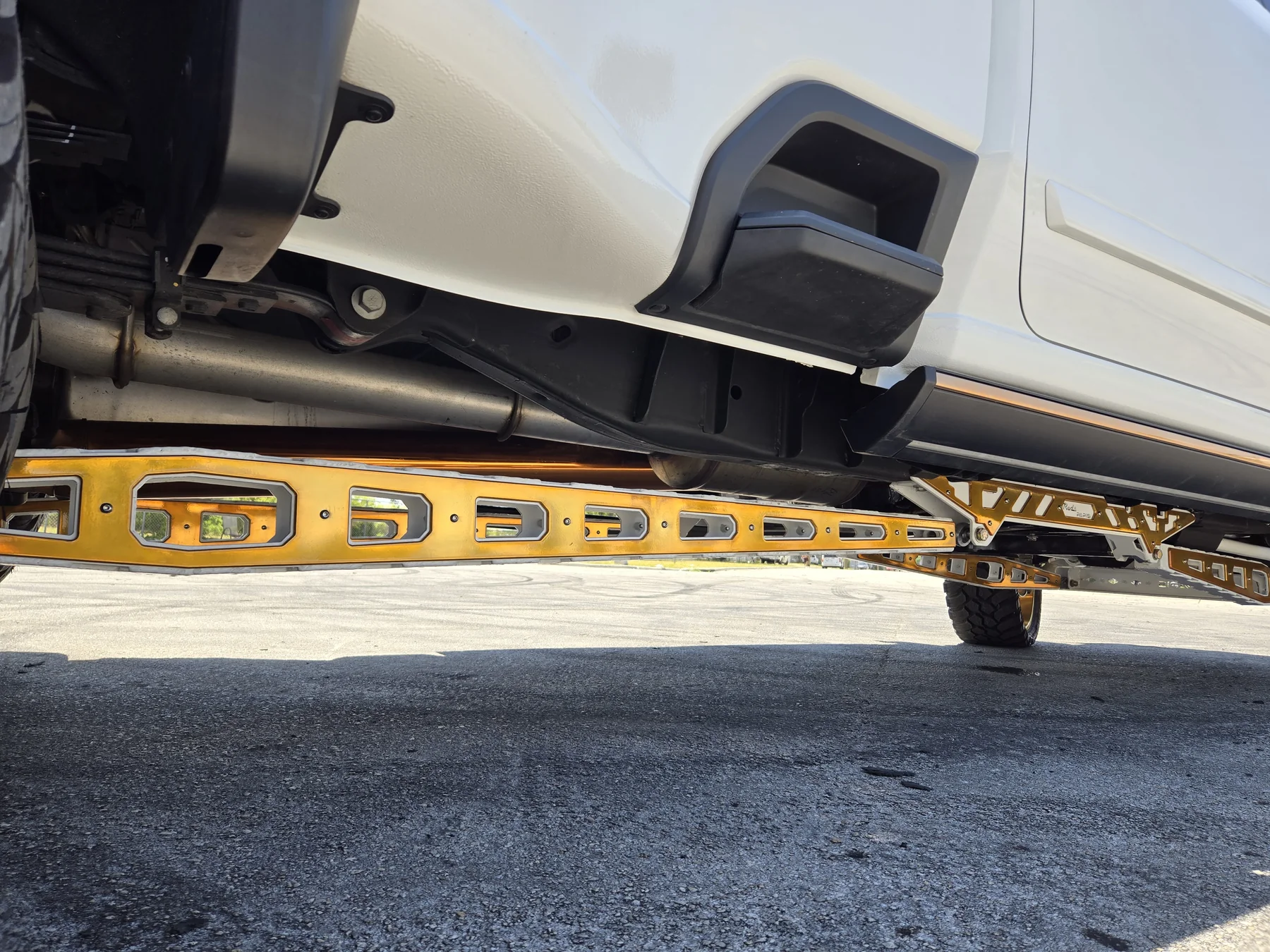 Gold custom running board and undercarriage detail on a white truck