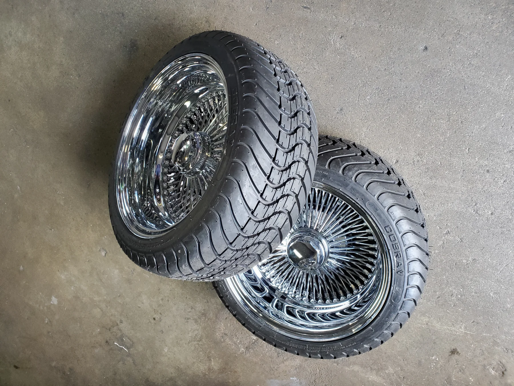 Chrome wire wheels and tires arranged on the Red's Miami shop floor